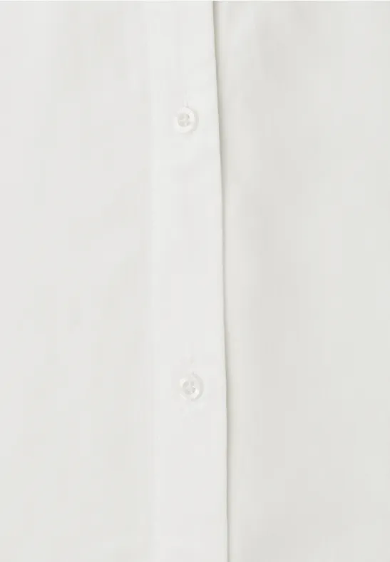 Gros plan sur la patte de boutonnage d'une chemise blanche avec des boutons.