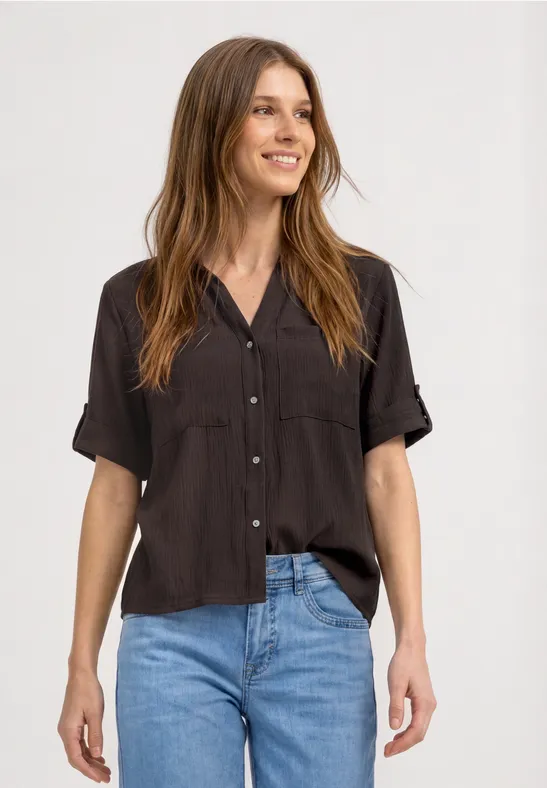 Eenvoudig zwart kort mouw blouse met knoopsluiting gecombineerd met blauwe jeans.