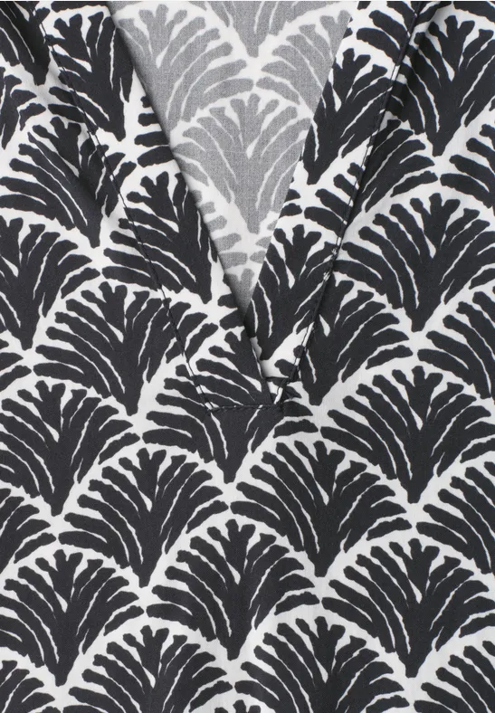 Close-up van een zwart-wit overhemd met herhaald bladpatroon in organisch design.