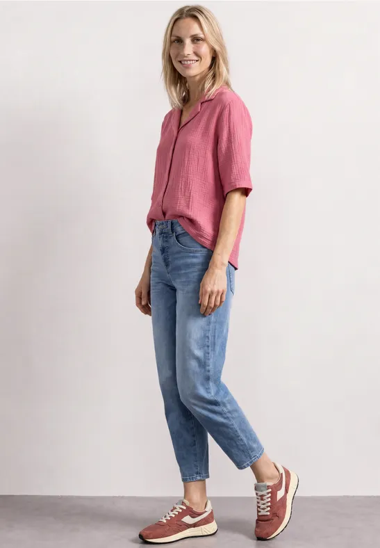 Femme souriante en chemise rose et jean debout