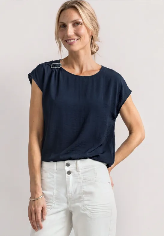 Vrouw met marineblauw mouwloos shirt en witte high-waist broek.