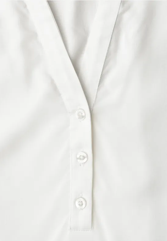 Chemise blanche à trois boutons sur la patte de boutonnage centrale.