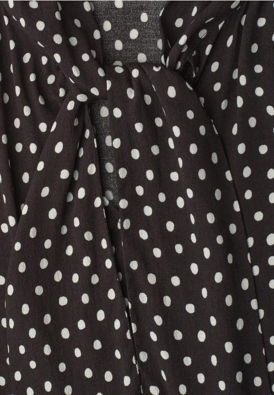 Tissu noir à pois blancs avec nœud, probablement un vêtement.