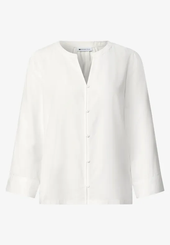 Chemisier blanc à manches longues, col rond et patte de boutonnage, sobre et élégant.