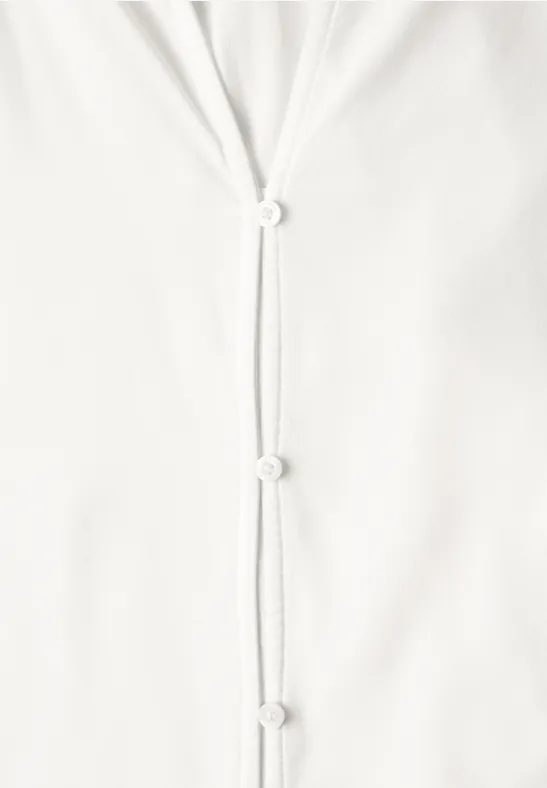 Gros plan sur un tissu blanc avec trois petites fermetures à boutons.
