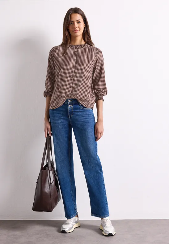 Femme en chemise ample marron, jean droit bleu, baskets blanches et grand sac cabas marron foncé.