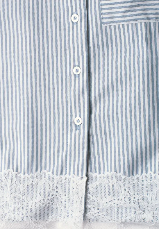 Gros plan d’un vêtement rayé bleu et blanc avec boutons blancs et bordure en dentelle