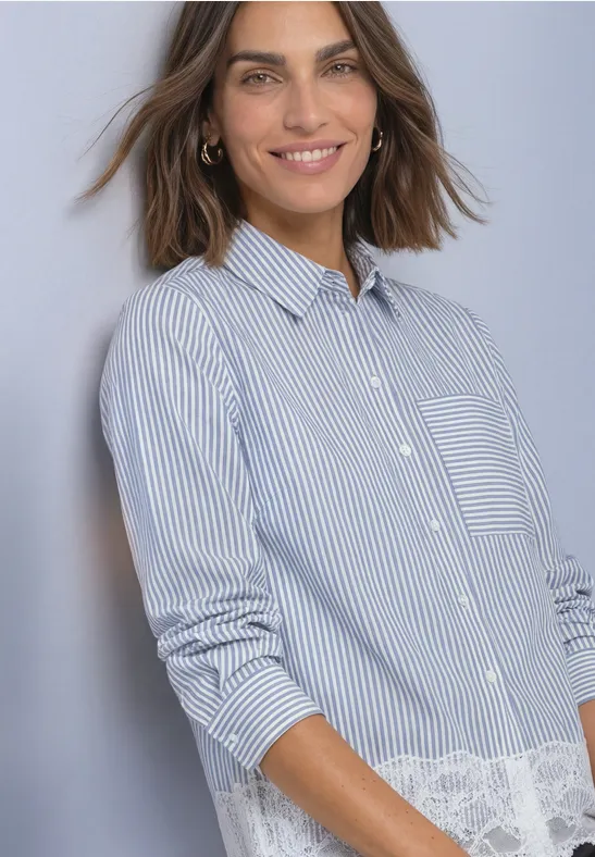 Femme souriante portant une chemise rayée bleu et blanc avec dentelle, posant devant un fond neutre.