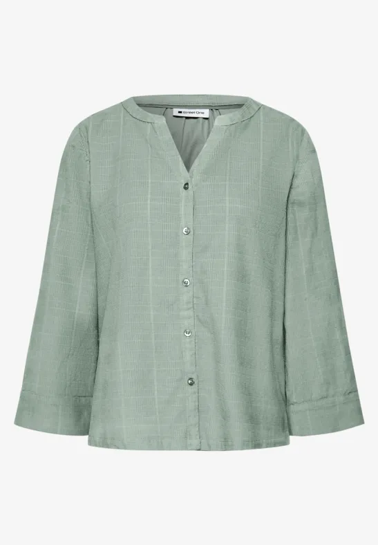 Losvallende lichtgroene blouse met V-hals, knoopsluiting en wijde mouwen.