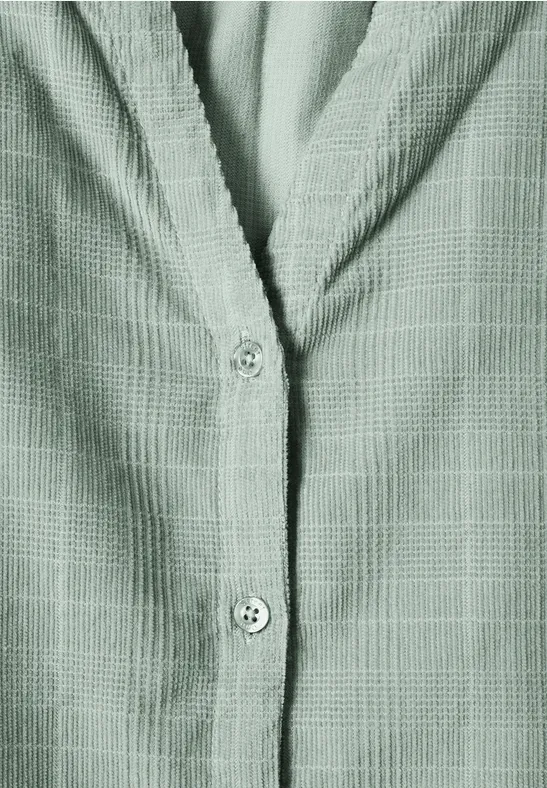 Groen textuur-overhemd met subtiel ruitpatroon, close-up van de knopenrij en de kraag.