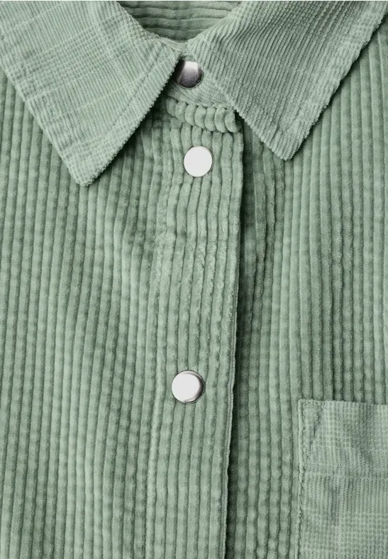 Veste en velours côtelé vert avec pressions blanches et poche plaquée.
