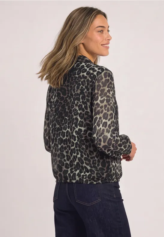 Une femme porte une veste ample imprimée léopard, vue de dos.