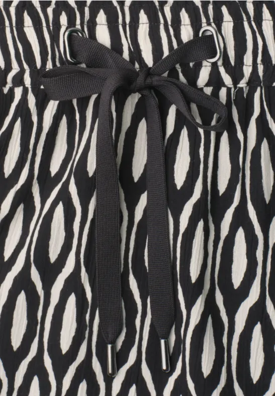 Tissu noir et blanc à motif d'ovales avec un ruban noir noué à la taille