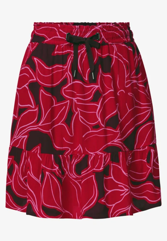 Rode rok met elastische taille, zwarte strik in de taille en abstract bloemenpatroon.