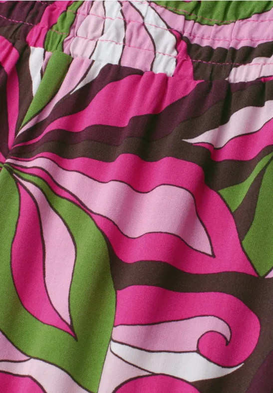 Bunt gemusterter Stoff mit geschwungenen Blüten- und Blattmotiven in Pink, Grün, Weiß und Braun