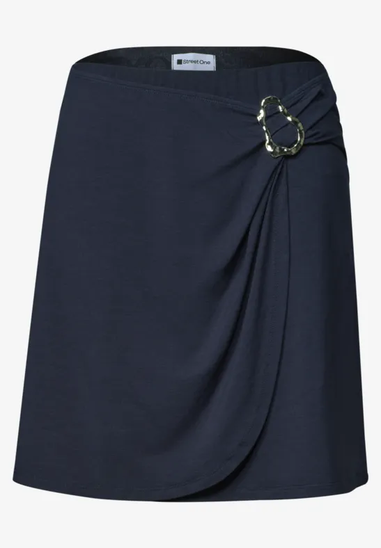 Jupe portefeuille bleu marine avec drapé latéral et boucle décorative couleur dorée.