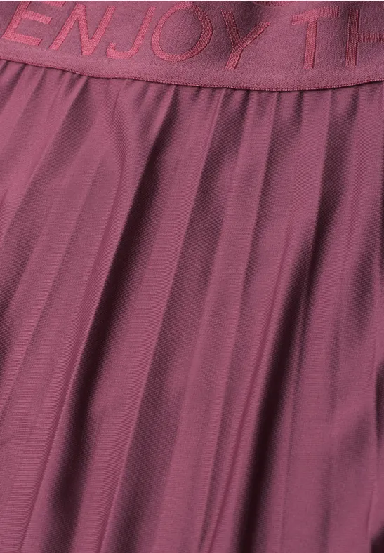 Close-up van een bordeaux plissé rok met elastische tailleband en ingelegd opschrift
