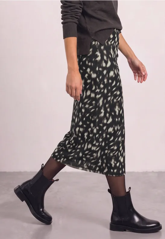 Gemusterter Midirock kombiniert mit schwarzen Leder-Stiefeletten.