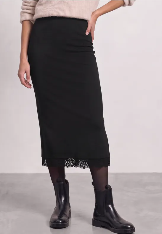 Femme porte une jupe midi noire à dentelle et des bottines noires