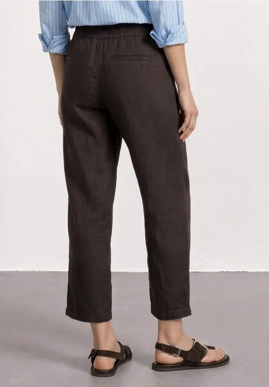 Persoon van achteren in donkergrijze, enkellange broek met sandalen.