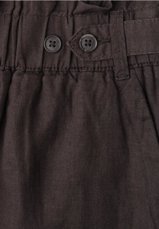 Close-up van een bruine broekband met elastische taille en twee knopen.