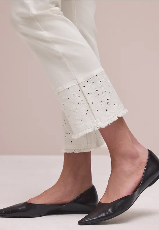 Weiße 7/8-Hose mit Lochstickerei am Saum und schwarze spitze Ballerinas.