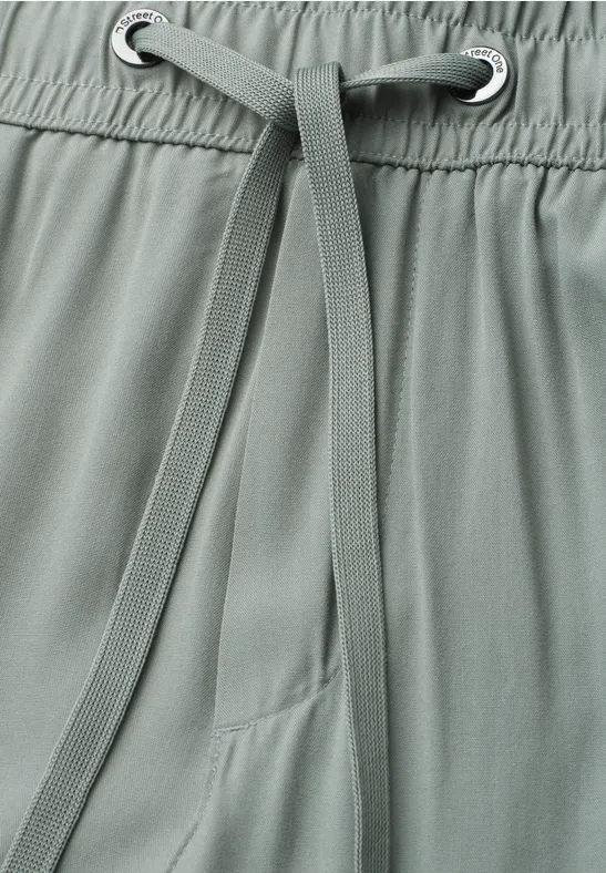 Close-up van een grijsgroene broek met aantrekkoord en elastische taille