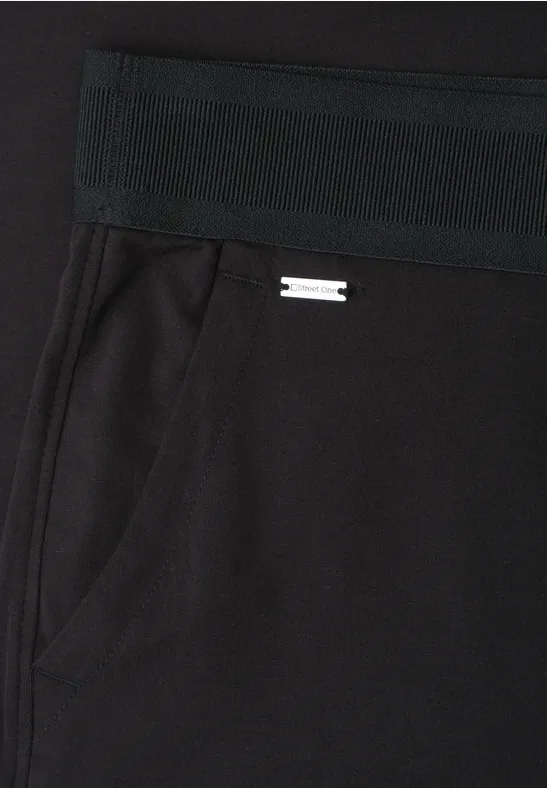 Schwarze Hose mit elastischem Bund, seitlicher Tasche und kleinem Metalllogo.