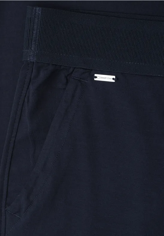 Donkere sportbroek met elastische taille, zijzak en klein metalen logo.
