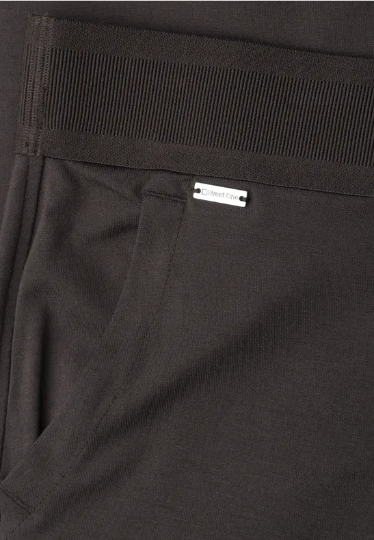 Zwarte broek met zijzak en een klein zilverkleurig label boven de zak.