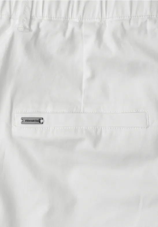 Wit kledingstuk met achterzak en klein metalen label aan de achterkant.