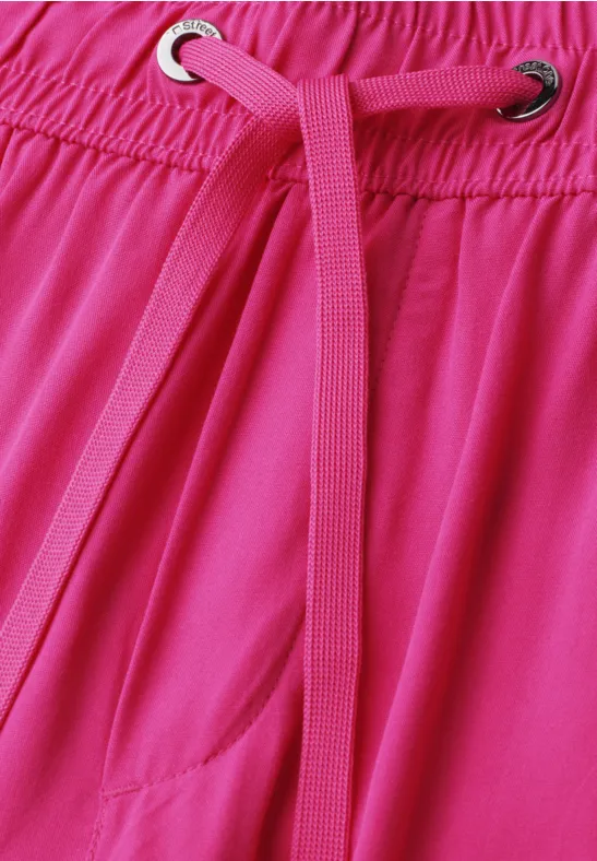 Gros plan d'un vêtement rose à taille élastique avec cordon rose passant dans des œillets métalliques.