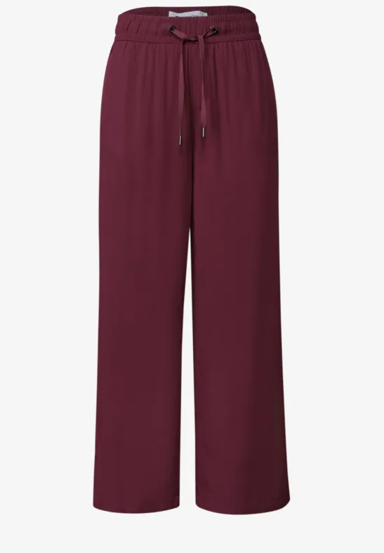 Bordeauxrode wijde broek van stof met elastische taille en trekkoord.