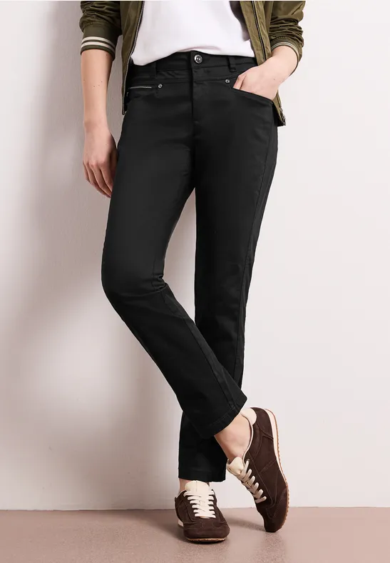 Jean noir et baskets bicolores, assortis à un t-shirt blanc et une veste sur fond clair.