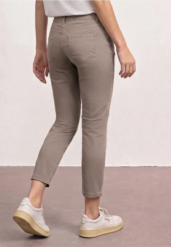 Vue arrière d’une personne portant un pantalon taupe ajusté et des baskets blanches.