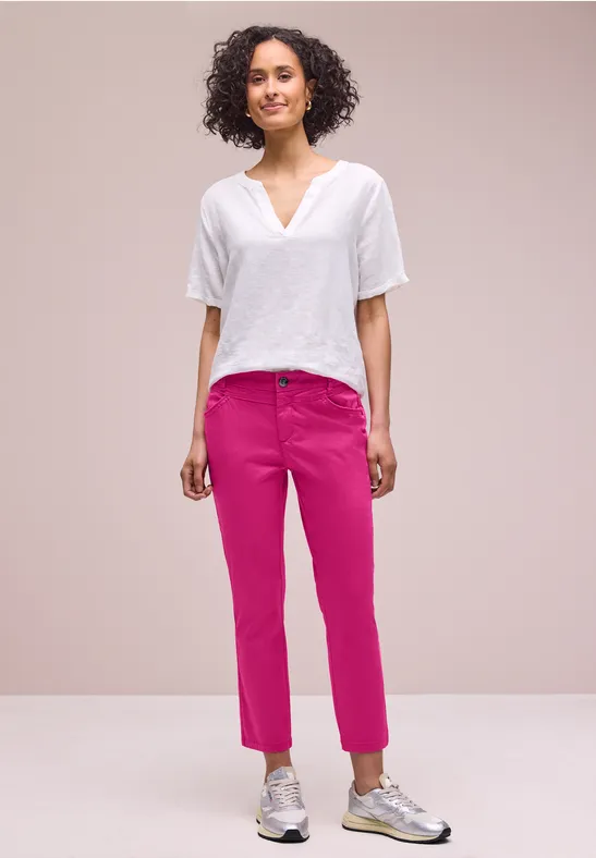 Persoon met wit shirt en roze broek voor lichte achtergrond.