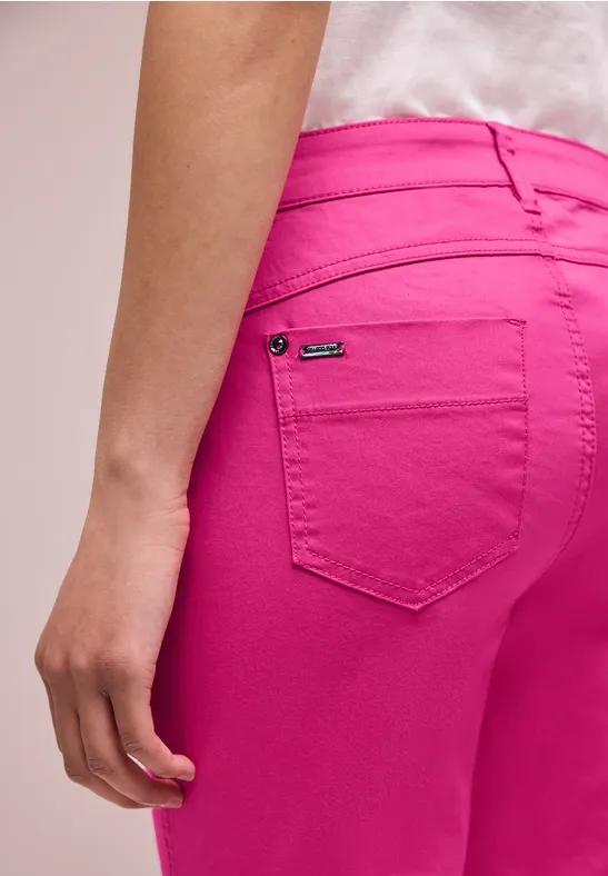 Zijaanzicht van een persoon in felroze jeans met zichtbare achterzak en ontspannen hangende arm.