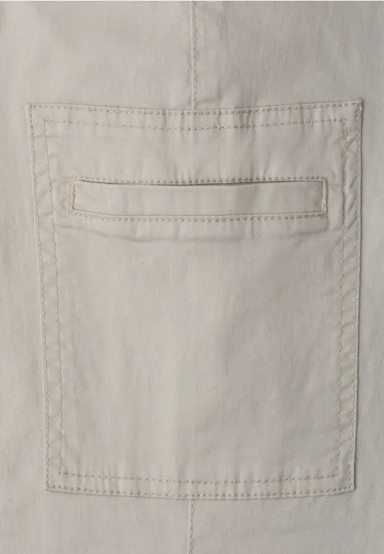 Beige katoenen stof met opgestikte zak en zichtbare sierstiksels.