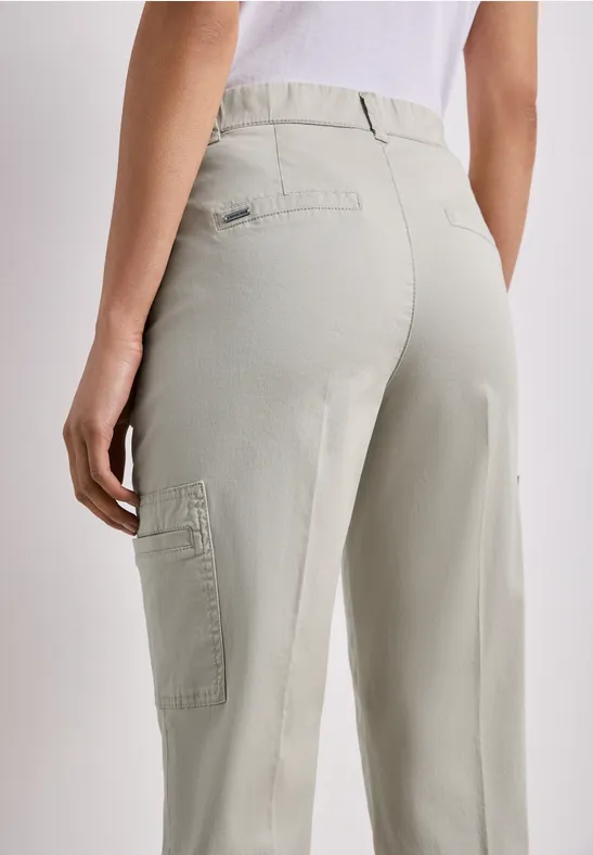 Achteraanzicht van een persoon in lichtgrijze cargobroek met een zijzak op de dij.