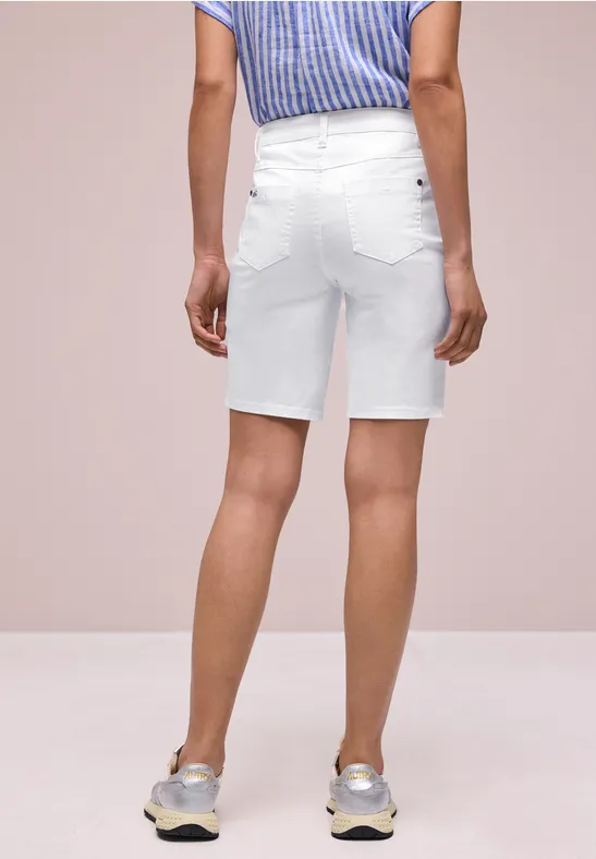 Achteraanzicht van een persoon in witte jeansshort, blauw-wit gestreept topje en lichte sneakers.