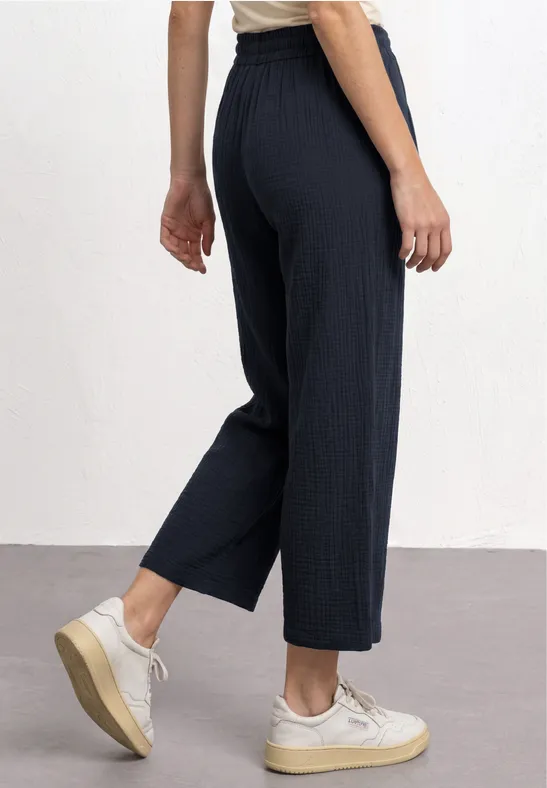 Wijd geribd donkerblauw 3/4-broek met elastische taille, gecombineerd met witte sneakers.