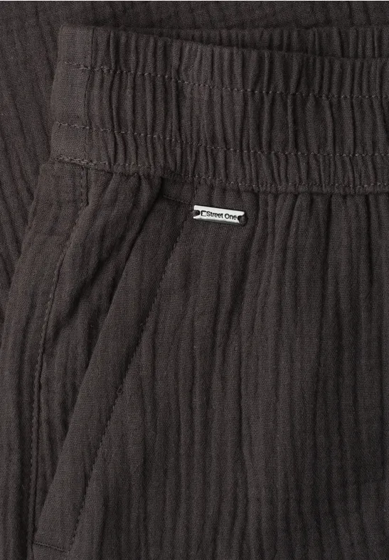 Zwarte geribde broek met elastische taille, zijzak en klein metalen label.