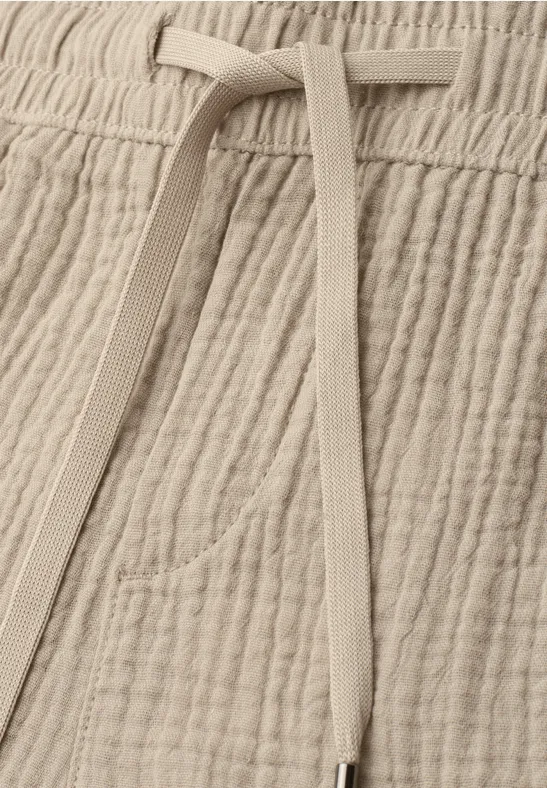 Pantalon beige en coton gaufré avec cordon de serrage et poche discrète.