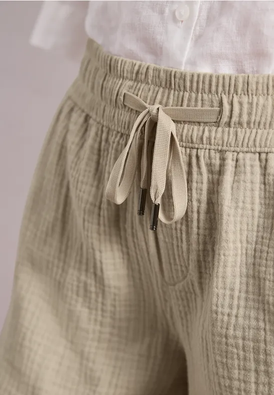 Vue sur un pantalon en lin beige texturé à cordon de serrage et un haut en lin blanc.