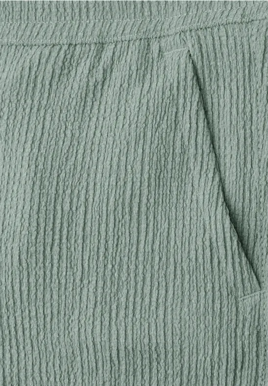 Gros plan d'un pantalon vert menthe texturé avec couture de poche