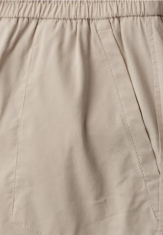 Close-up van een beige katoenen broek met elastische tailleband en zijzak