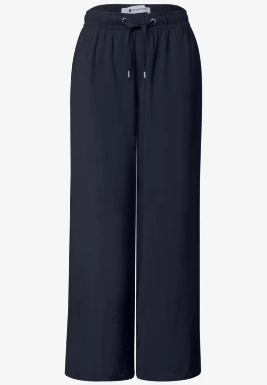 Zwarte, losse, wijde broek met elastische taille en koord, gemaakt van soepel materiaal.