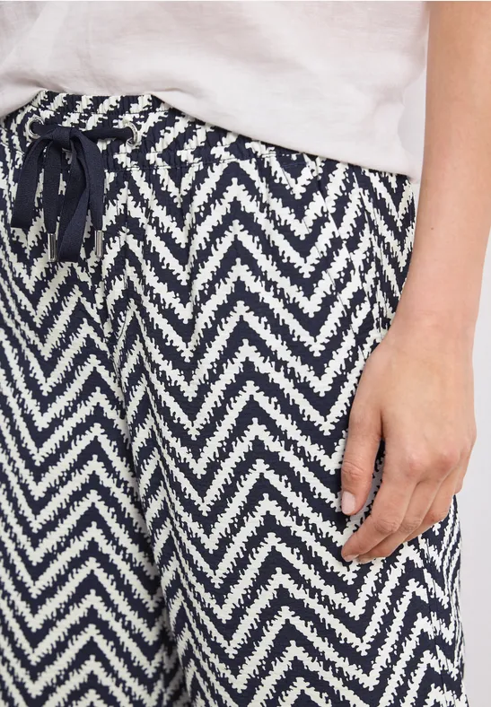 Close-up van een wit T-shirt en marineblauw-wit zigzagbroek met trekkoord.