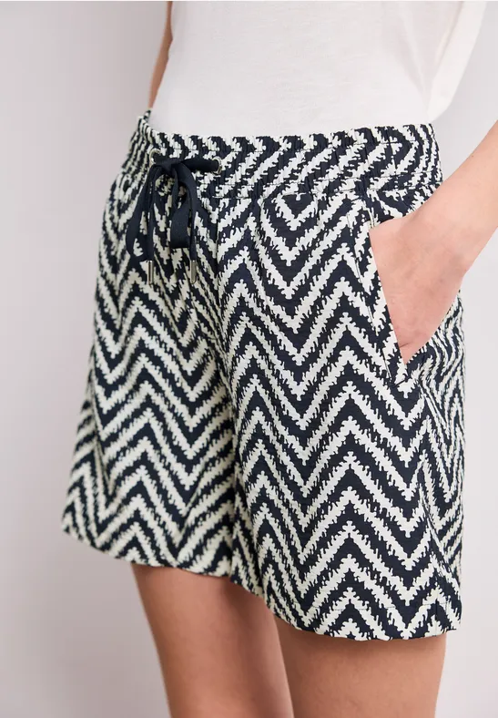 Damesshort met blauw-wit zigzagpatroon, trekkoord in de taille en steekzakken, informele stijl.