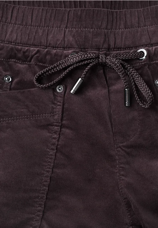Donkerrode ribfluwelen broek met elastische taille, gevlochten trekkoord, metalen oogjes en uiteinden.